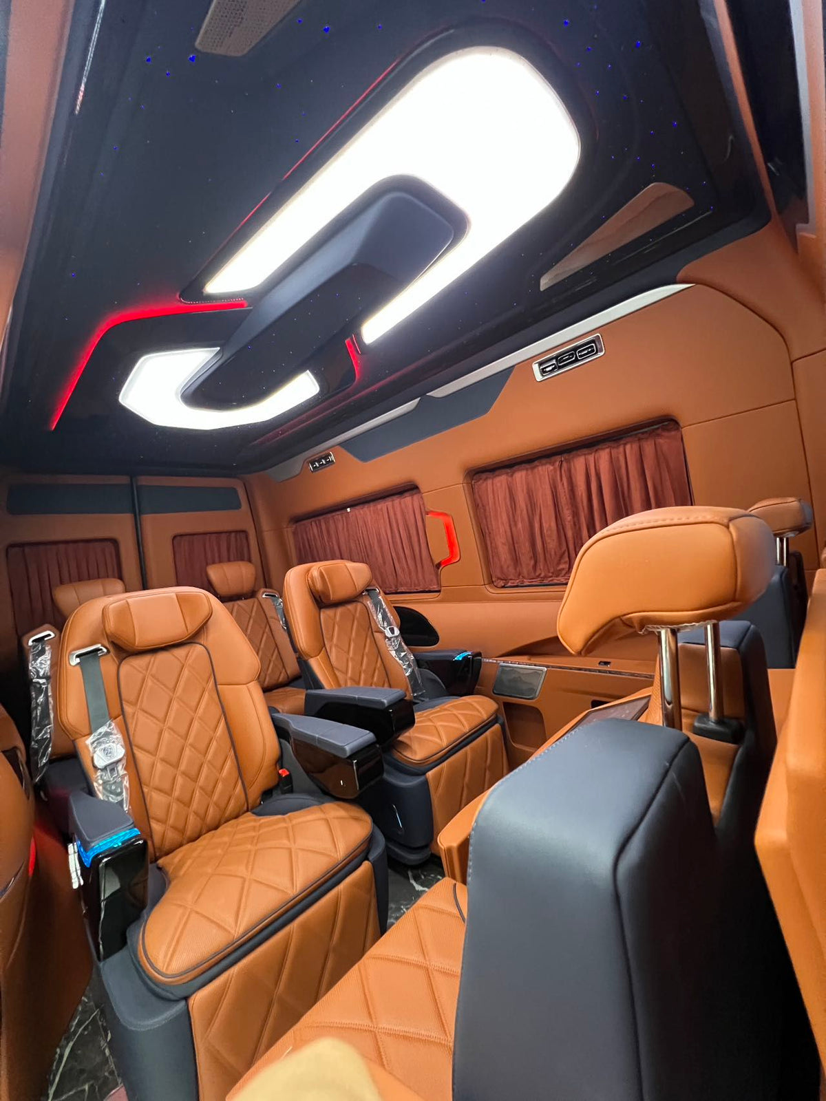 Toyota HiAce upgrade package: luxury seating, waterproof flooring, electric curtains, and a concealed bar/seating unit.
